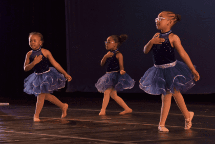 Three girls wearing the blue dress and performing the dance on the stage